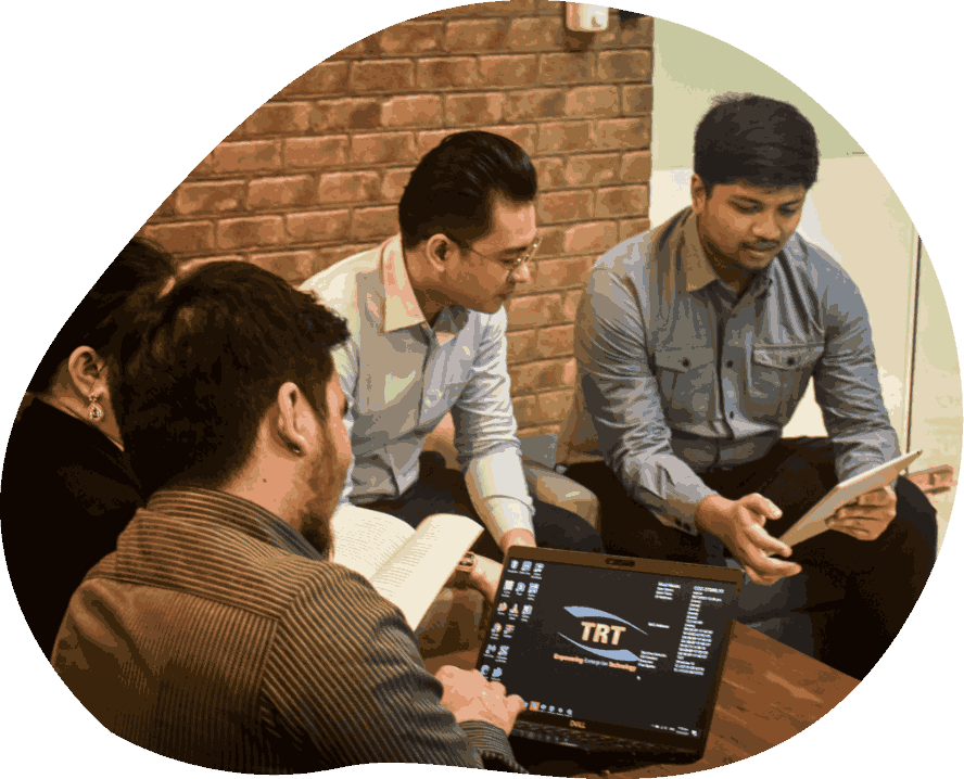 Three individuals engaged in work at a table, each using their laptops for collaboration or study.
