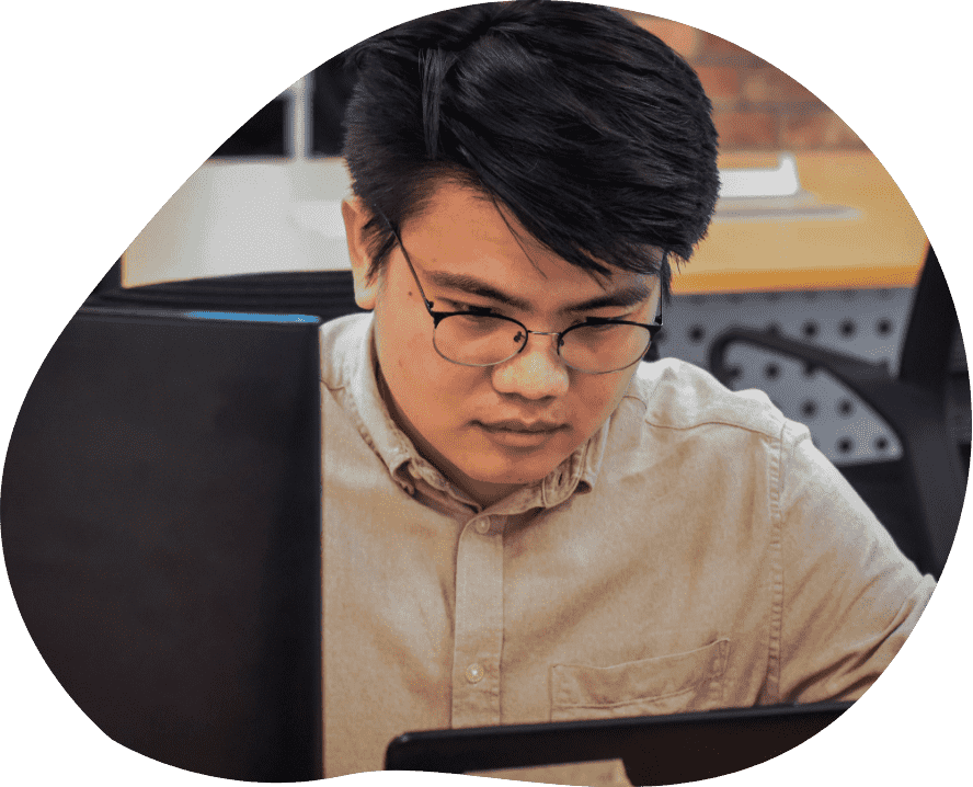 A man wearing glasses is focused on his laptop, engaged in work at a desk. 24/7 IT Support