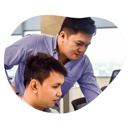 Two men in an office, focused on a computer screen, collaborating on a project together.